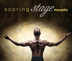 A shirtless man with tribal tattoos on his back and arms stands with arms outstretched, holding a conductor's baton.