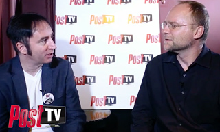 Two men in dark shirts sit facing each other during an interview in front of a Post TV logo backdrop.