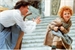 A man in a white shirt reaches toward a small child running up stone stairs.