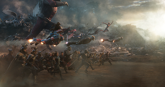 Numerous figures fight amidst smoke and rubble in a large-scale cinematic battle scene.