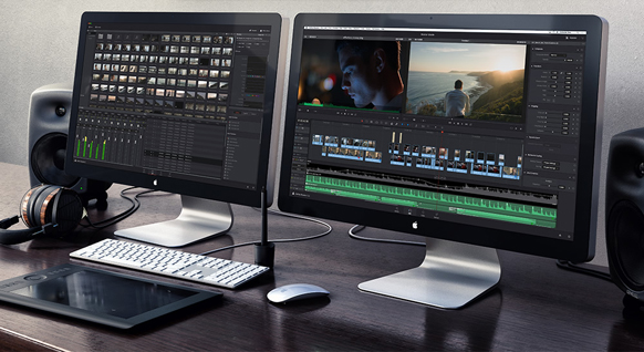 Two computer monitors displaying video editing software on a dark desk with speakers and peripherals.