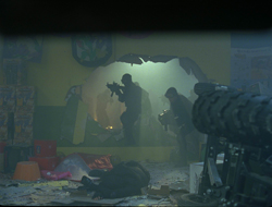 Silhouetted armed figures move through a smoke-filled room with a large breach in the wall.