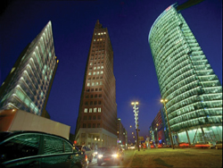 Low-angle shot of three tall skyscrapers reaching toward a dark blue night sky.