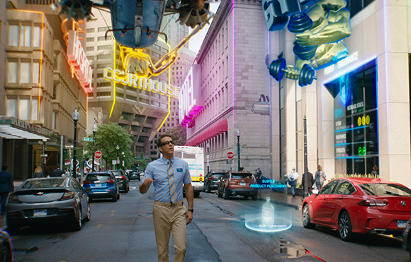 A man in a blue shirt walks down a city street with holographic signs and flying vehicles overhead.