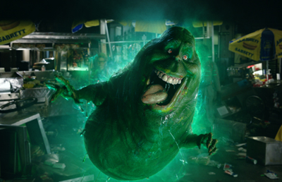 A large, translucent green ghost with a wide mouth and sharp teeth glowing in a dark setting.