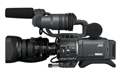 A black JVC professional video camera with a large lens and a shotgun microphone attached on top.