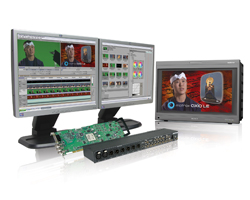 Two computer monitors showing video editing software and a portable monitor displaying a person's face.
