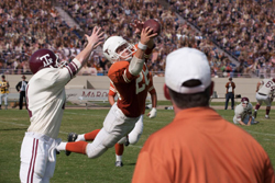 A football player in an orange jersey jumps mid-air to catch a football during a game.