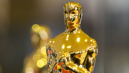 A close-up of a gold Academy Award statuette with a blurred background.