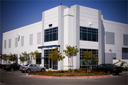 A white two-story modern office building with large windows under a clear blue sky.