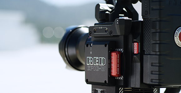 Close-up of a black RED EPIC-W digital cinema camera with a red media card inserted.