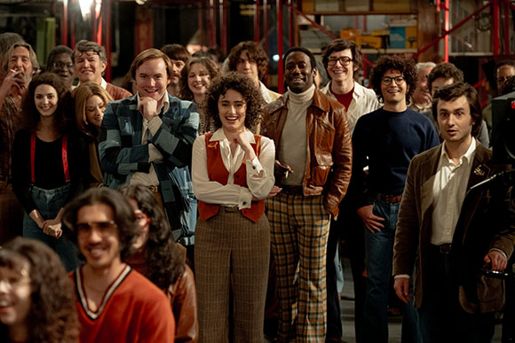 A large group of diverse people smiling and looking forward in a dimly lit indoor space.