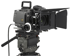 A professional cinema camera with a large lens and matte box mounted on a heavy-duty tripod head.