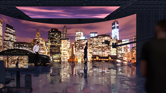 A film crew works in a studio featuring a massive curved LED screen showing a glowing city skyline at night.