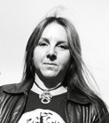Black and white portrait of a person with long hair, wearing a leather jacket and a necklace.