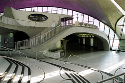 A wide view of a modern building interior featuring curved concrete stairs, railings, and large windows.