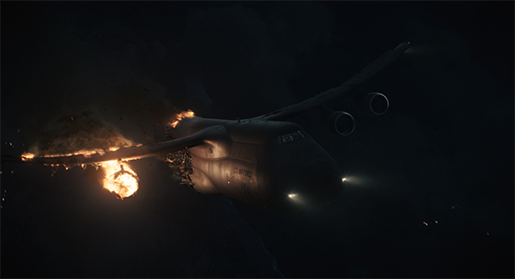A large military transport plane with fire and smoke trailing from its left wing in the dark.
