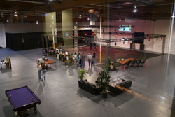 High-angle view of a large open warehouse event space with people, tables, and a pool table.