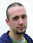 A man with short hair and a goatee wearing a blue hoodie over a green shirt.