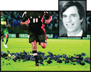 A soccer player in a dark jersey with number 11 runs on a field, next to a black and white portrait of a man.